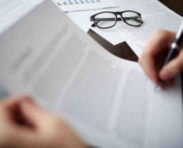 Image of business objects with businessman hand signing contract near by